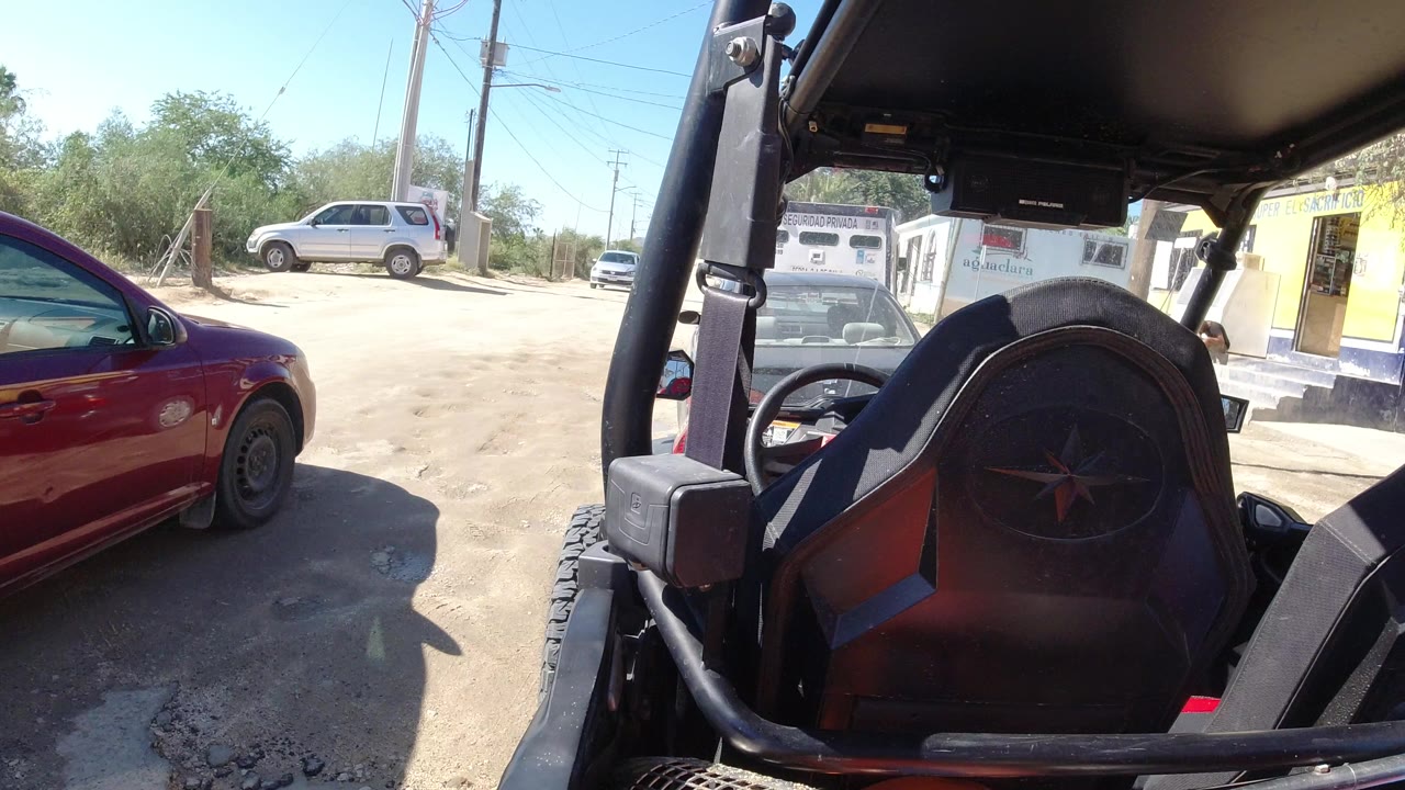 Open Wrangler interior beside a red sedan on a dusty roadside