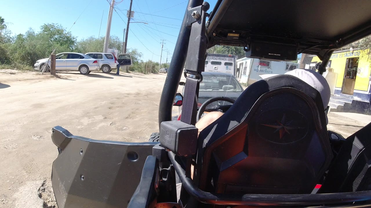 Parked Wrangler interior facing a dusty roadside with cars and shrubbery