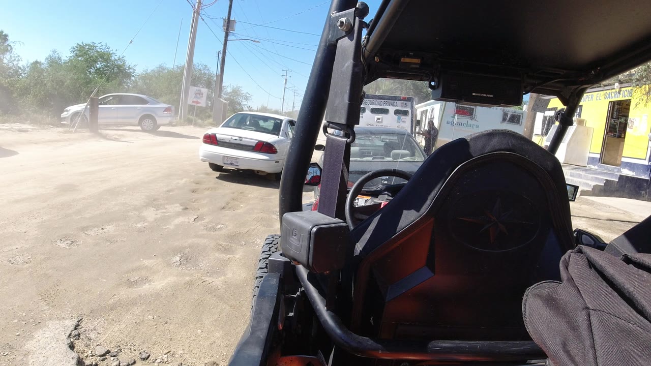 Dusty road with cars and Wrangler seat in foreground.