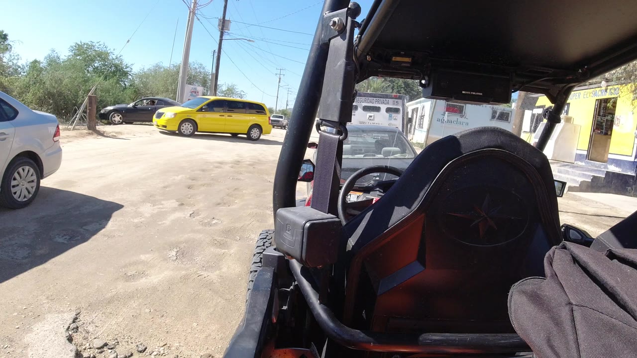 Open vehicle interior beside a dusty parking lot with parked cars.