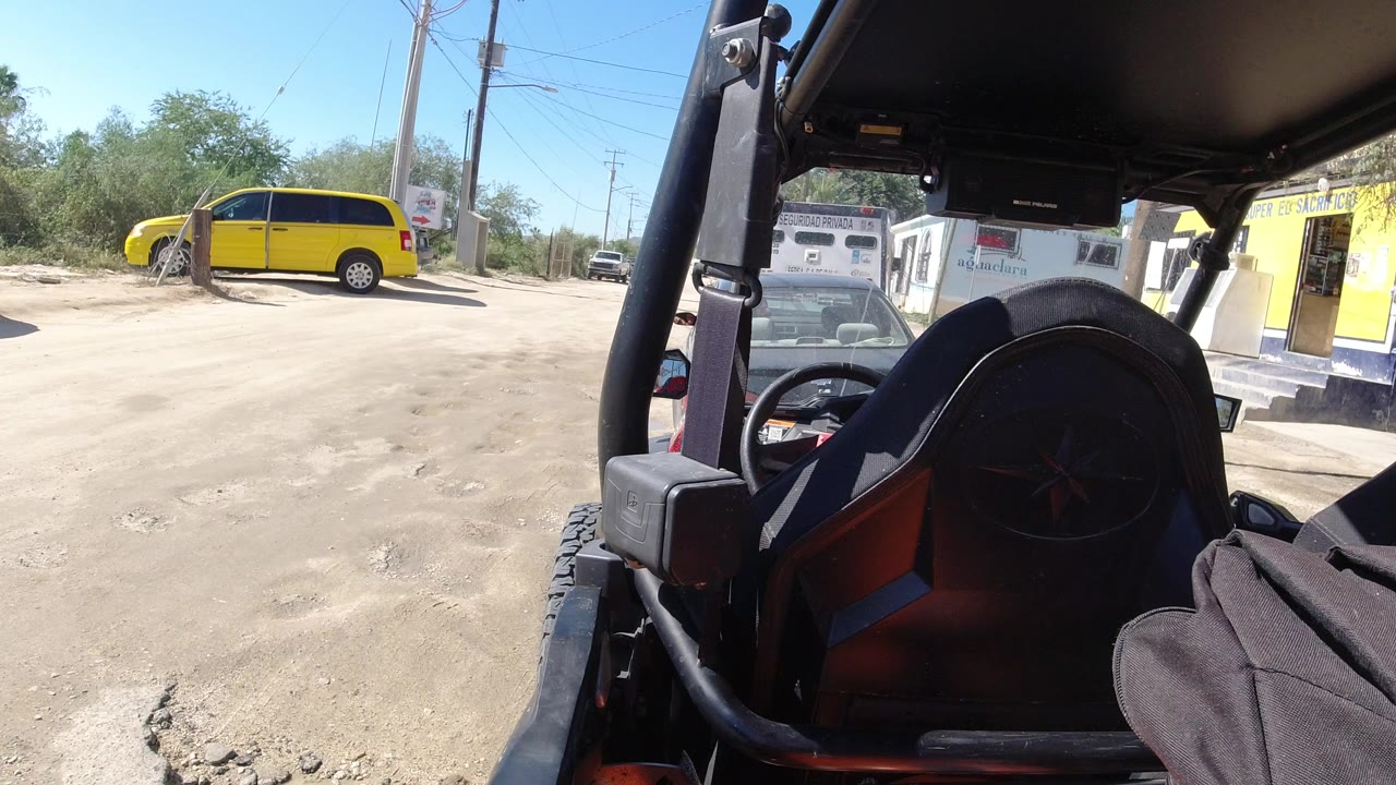 Dusty roadside lot with yellow van and vehicle seat foreground.