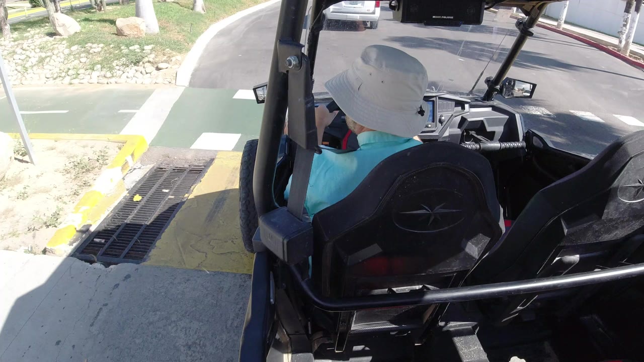 Driver in an open vehicle beside a curb and drainage grate
