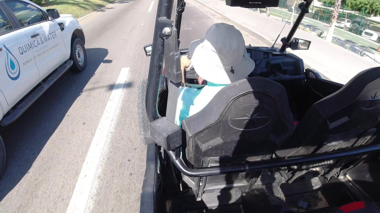 Open vehicle following a white service truck on a sunny road