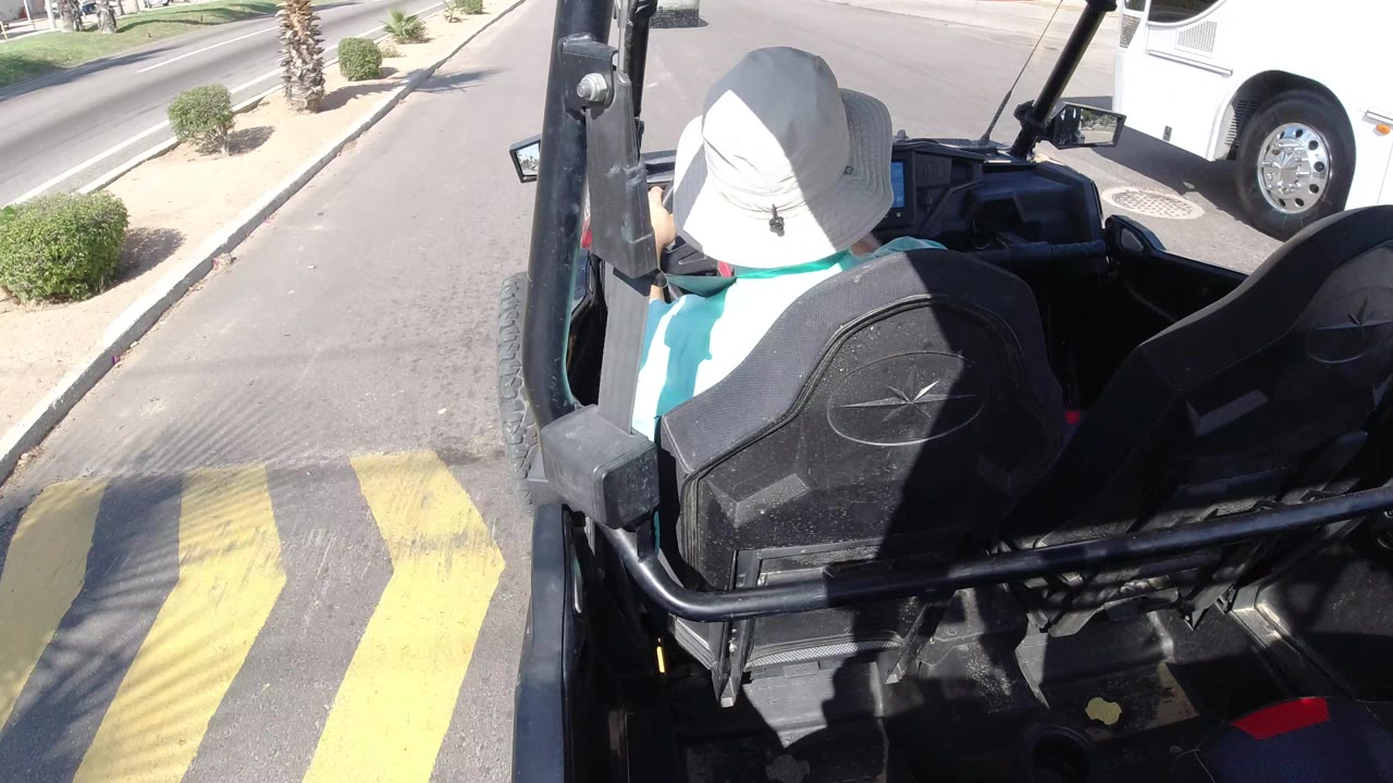 Vehicle passing over yellow speed bumps on a divided street.