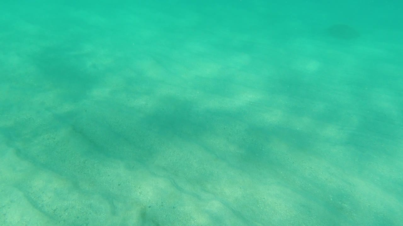 Filtered light on sand below clear water