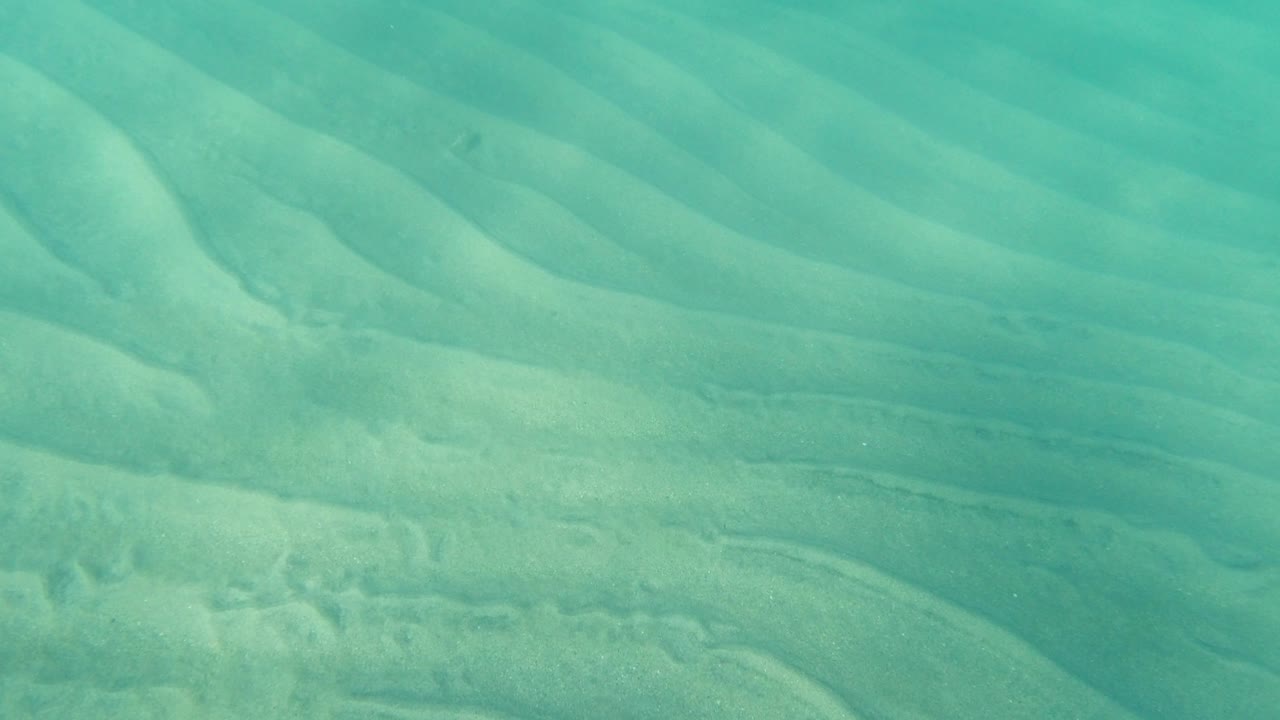 Second frame from Los Cabos, Mexico showing wavy sandy ridges under clear green-blue water with no visible people.