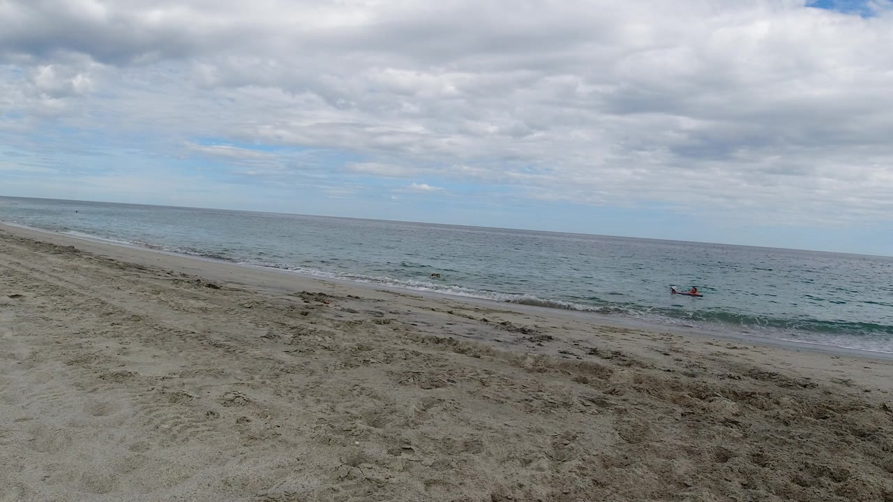 Open beach, blue-gray ocean, and clouds