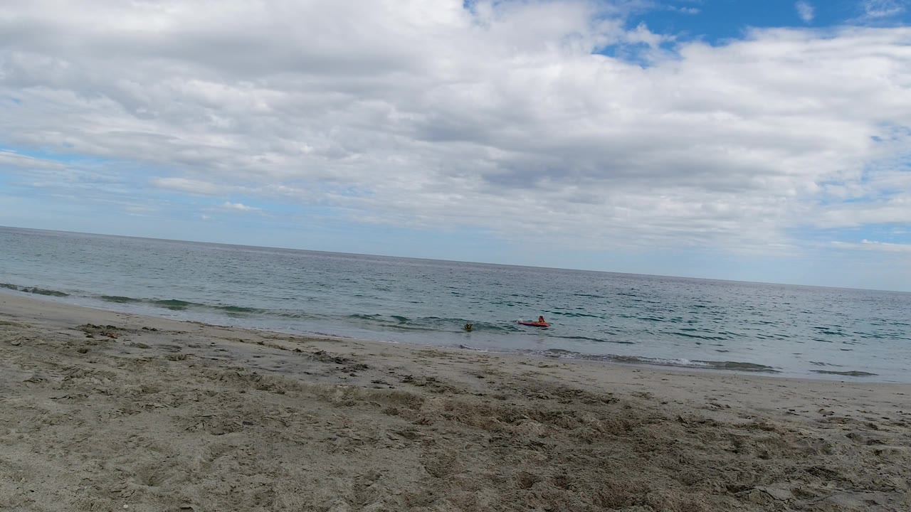 Cloudy ocean horizon with low waves and beach foreground.