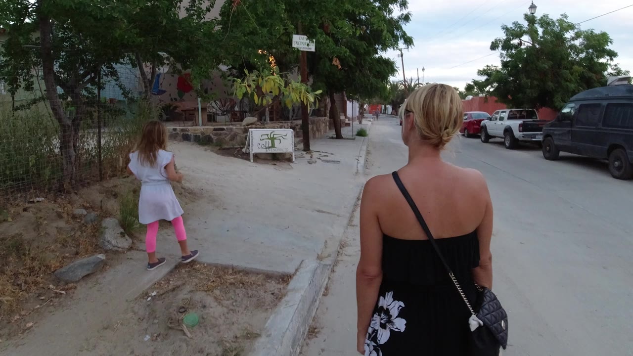 Woman and child walking along a quiet street from behind.