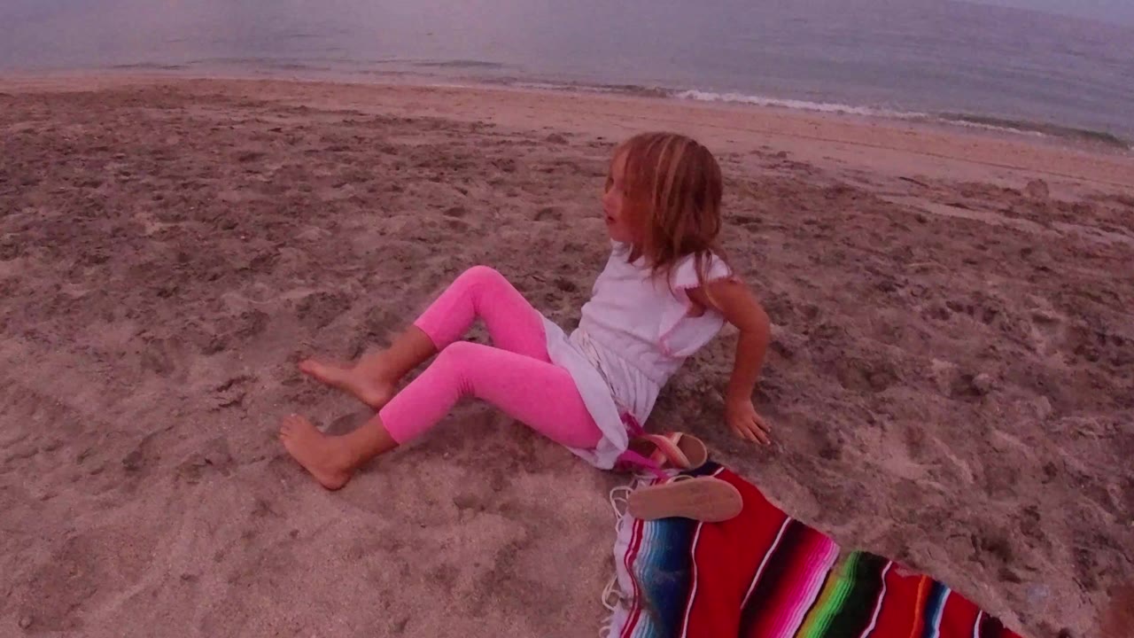 Young girl seated on sand above the shoreline