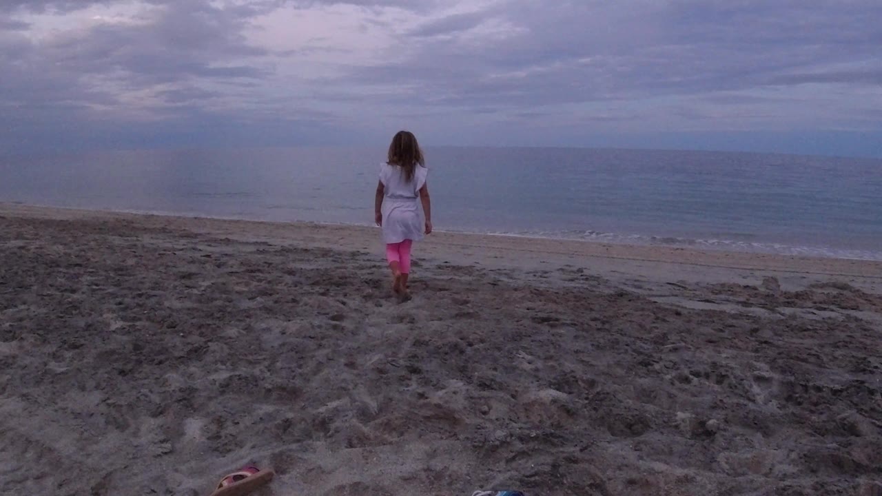 One second in, the girl remains centered on the open Los Cabos beach, with rippled sand in front of her and the ocean filling the background.