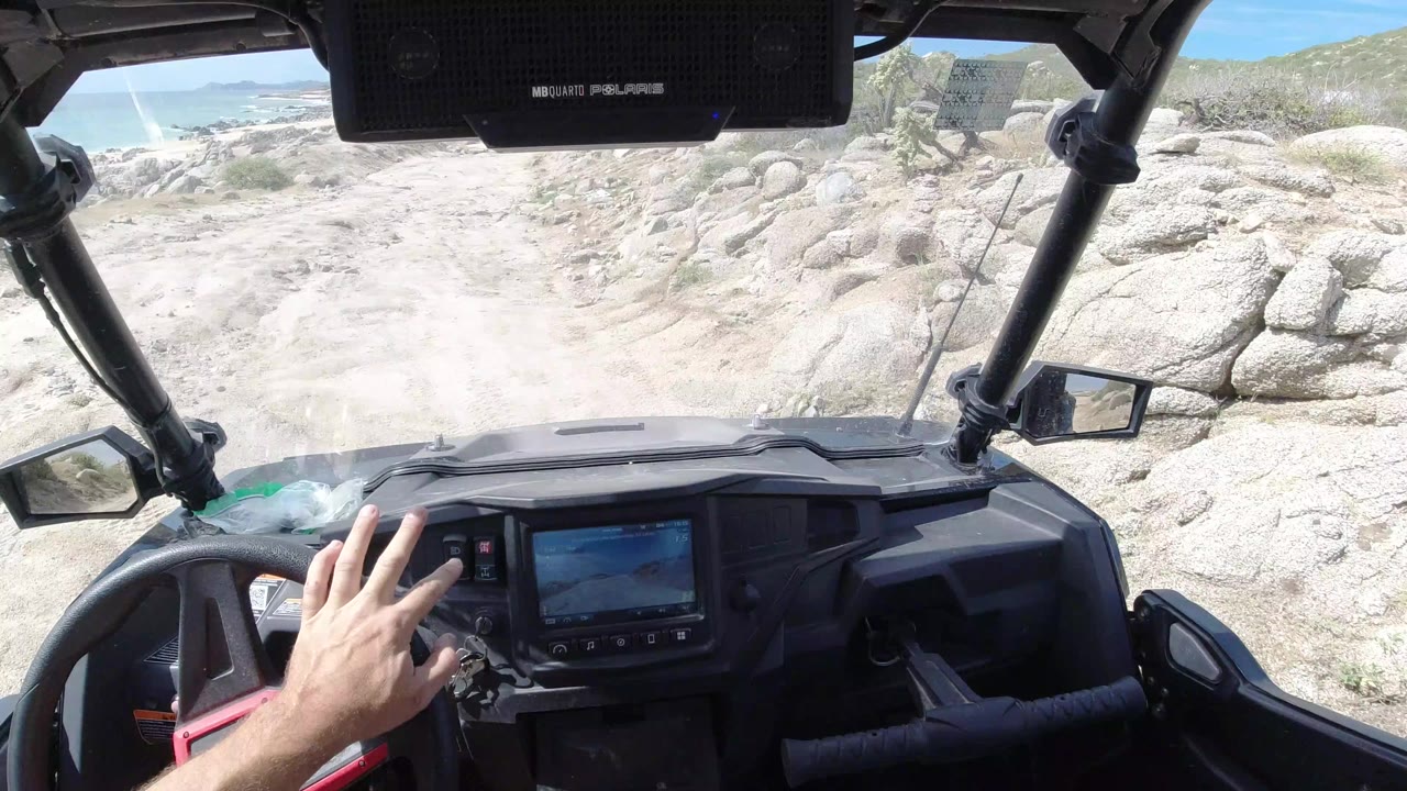 ATV dashboard facing a sandy rocky trail near the beach