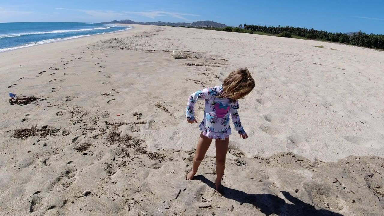 Young girl standing on sandy beach near the ocean