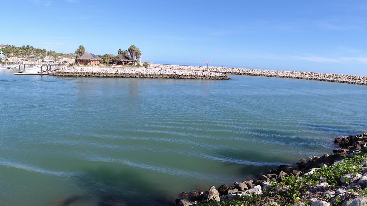 Rocky foreground shoreline facing open water and a low breakwater.