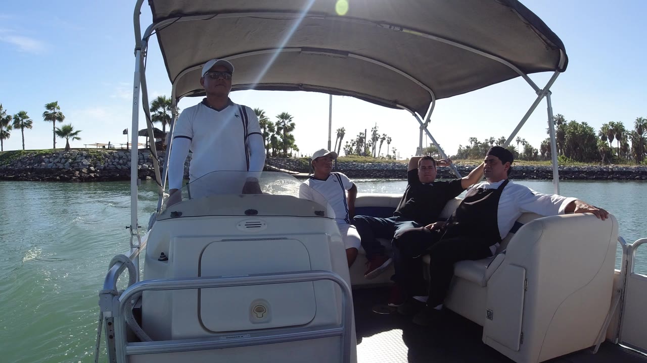 Adults and a child on a covered boat near a palm-lined shore.
