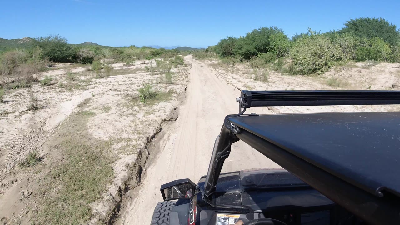 Narrow sandy track with scrub and Wrangler foreground.