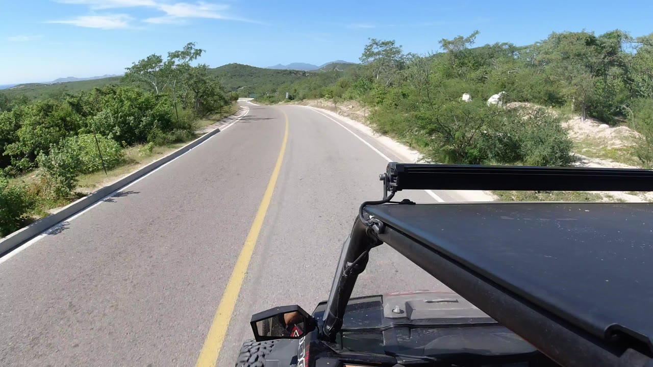 RZR foreground on a paved road through green brush and low hills
