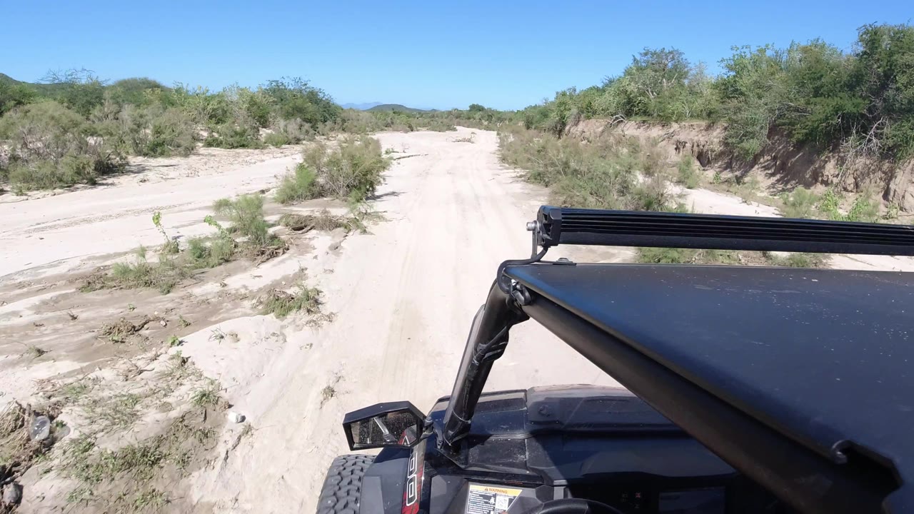 Wrangler foreground on a rutted sandy road with brushy banks.