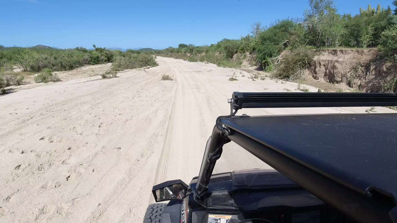 Sandy desert road seen over the front of an off-road vehicle.