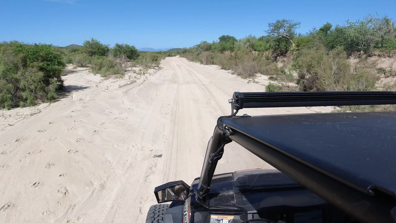 Off-road vehicle beside tire tracks on sandy terrain