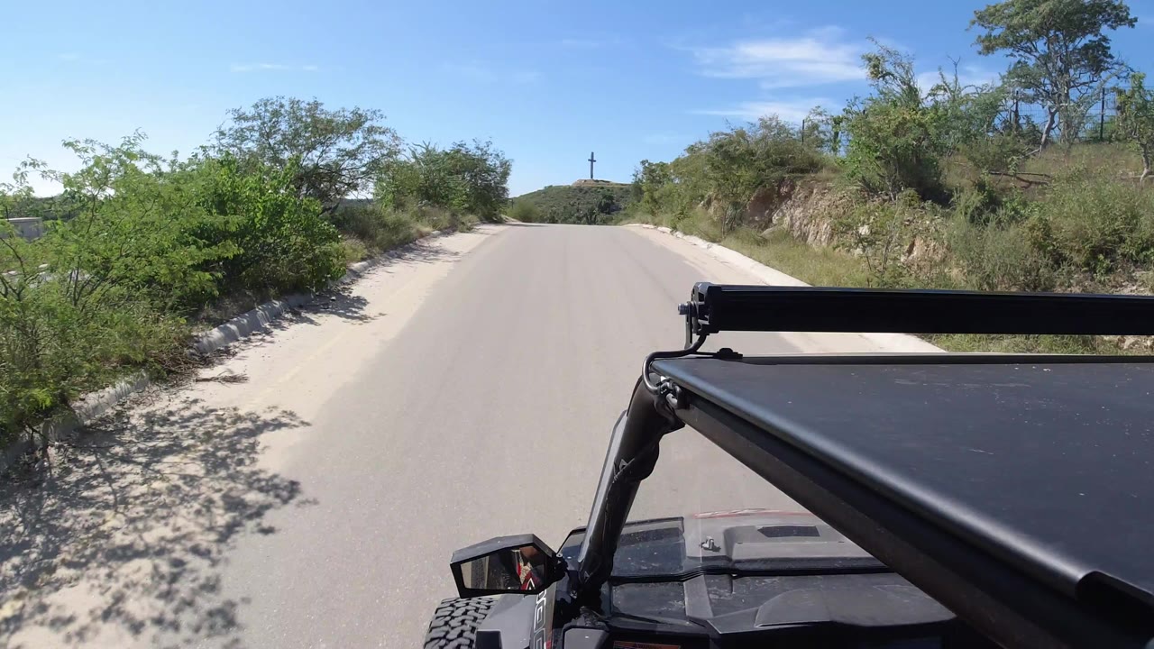 Wrangler foreground on a quiet paved road through shrubs and sand.