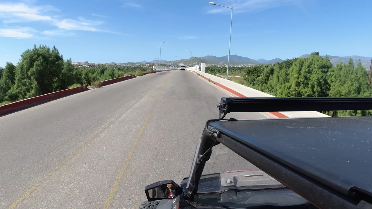 Road and bridge approach seen over Jeep hardware with mountains in the distance.