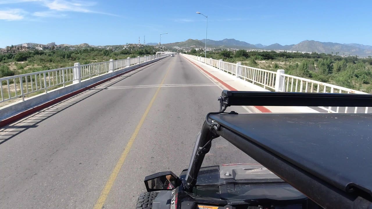 Forward road view from a Wrangler on a bridge with mountains ahead.