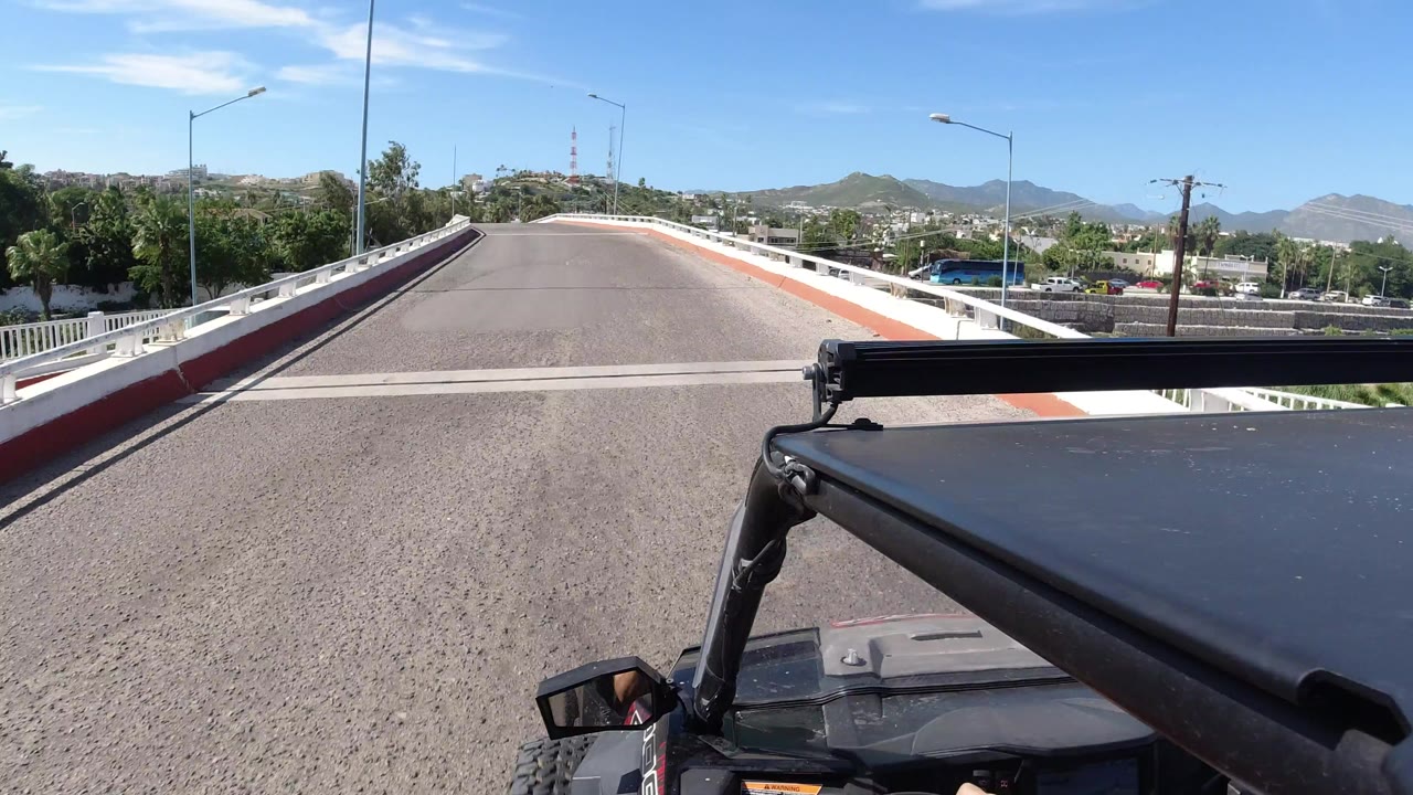 Wrangler foreground on a paved bridge under blue sky