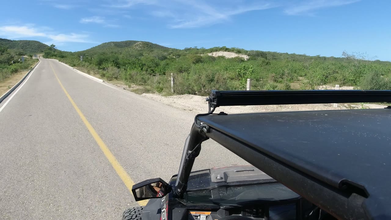 Paved road ahead of a Wrangler with desert brush and hills