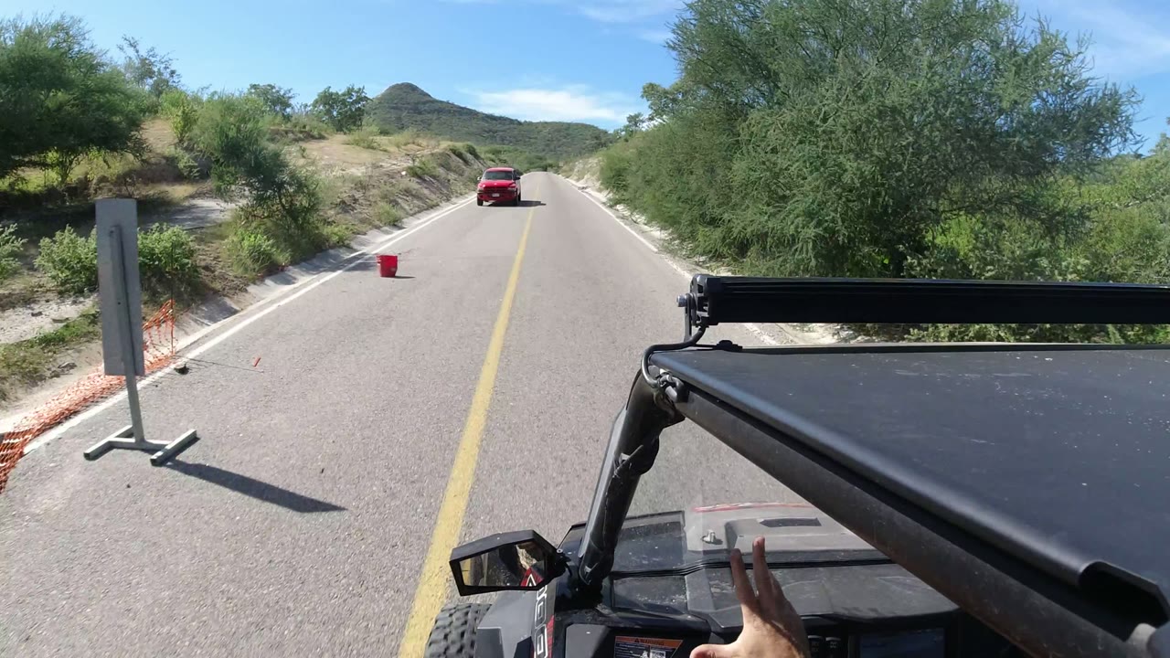 Two-lane road with a red vehicle ahead and Jeep hardware in the foreground.