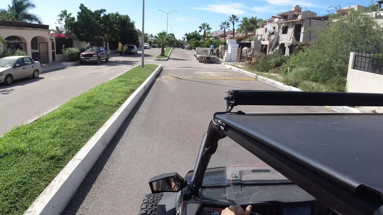 Wrangler roof foreground on a sunny residential street with palms and parked cars.