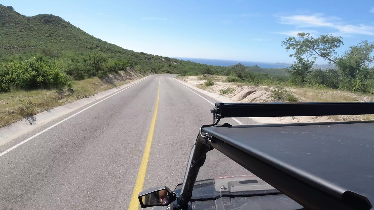 Straight desert road seen over a vehicle hood and light bar