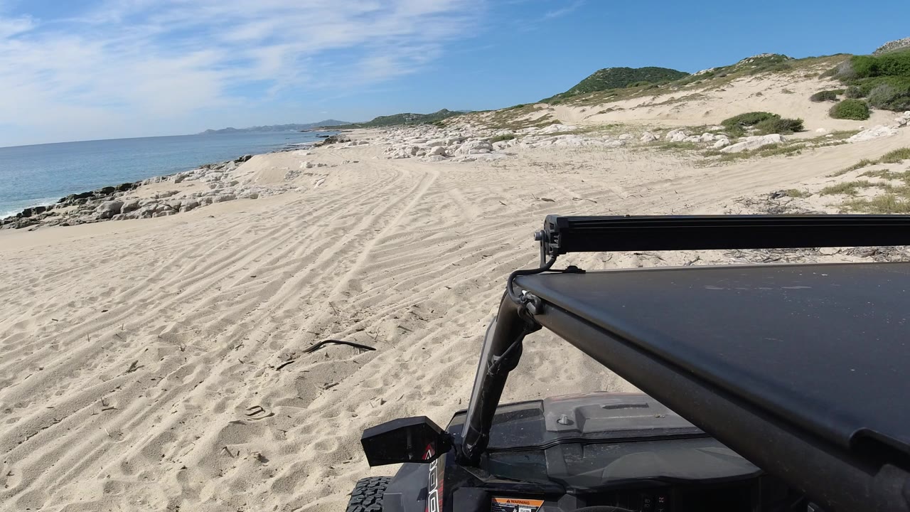 Wrangler foreground on sandy beach beside ocean and dunes