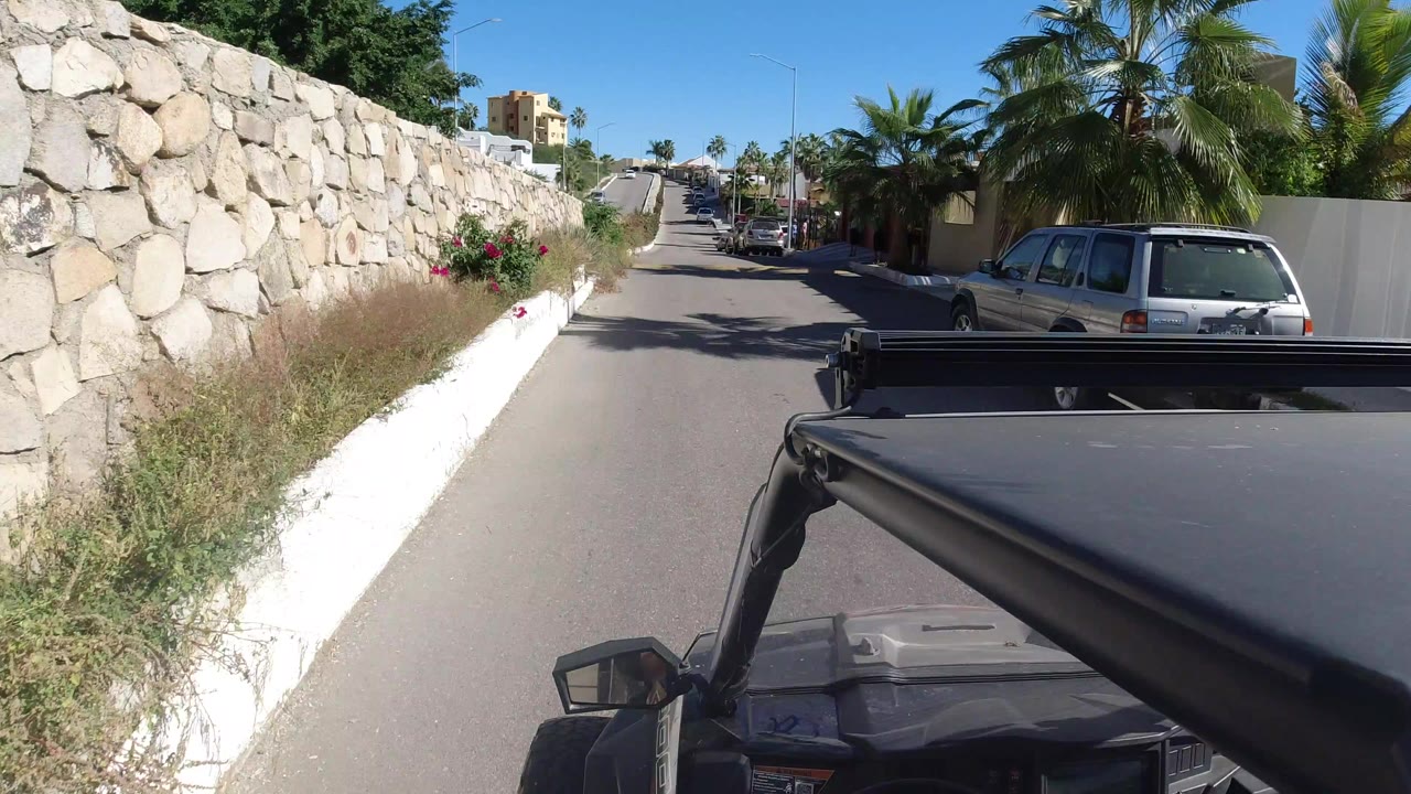 Jeep roof view on a sunny residential road beside a stone wall