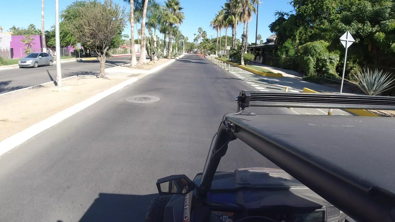 Forward road view from a Wrangler with palm trees and desert landscaping.