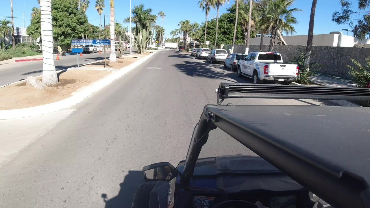 Wrangler foreground on a sunlit street with parked cars and palm trees.