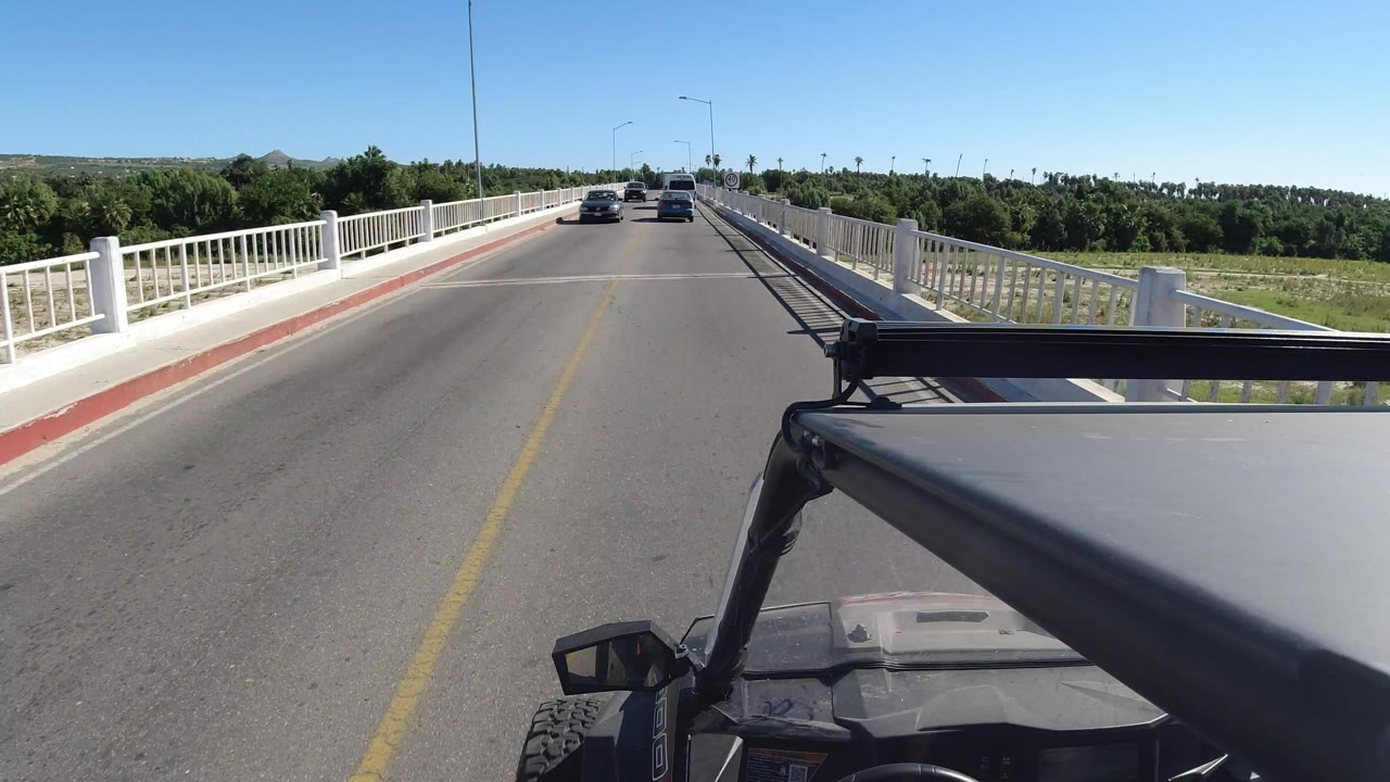Forward view from a vehicle crossing a bridge with cars ahead.
