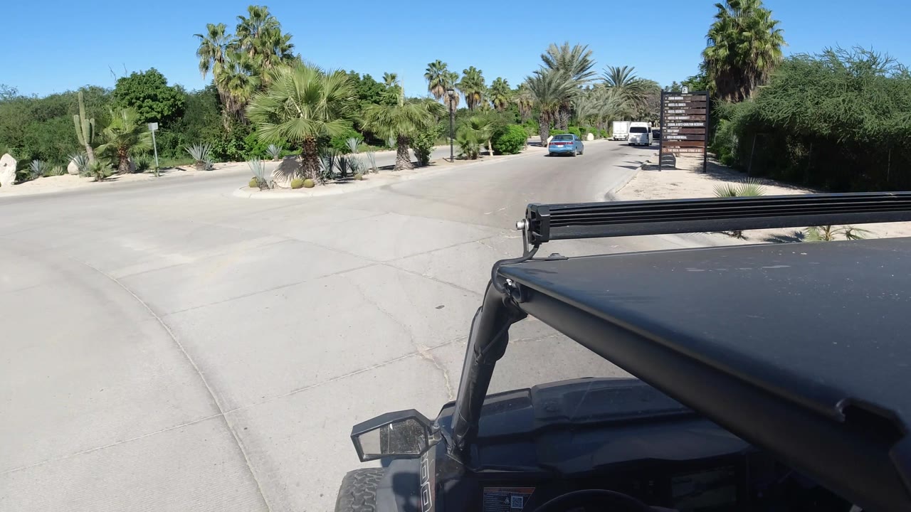 Jeep turning onto a wider road lined with palms and shrubs