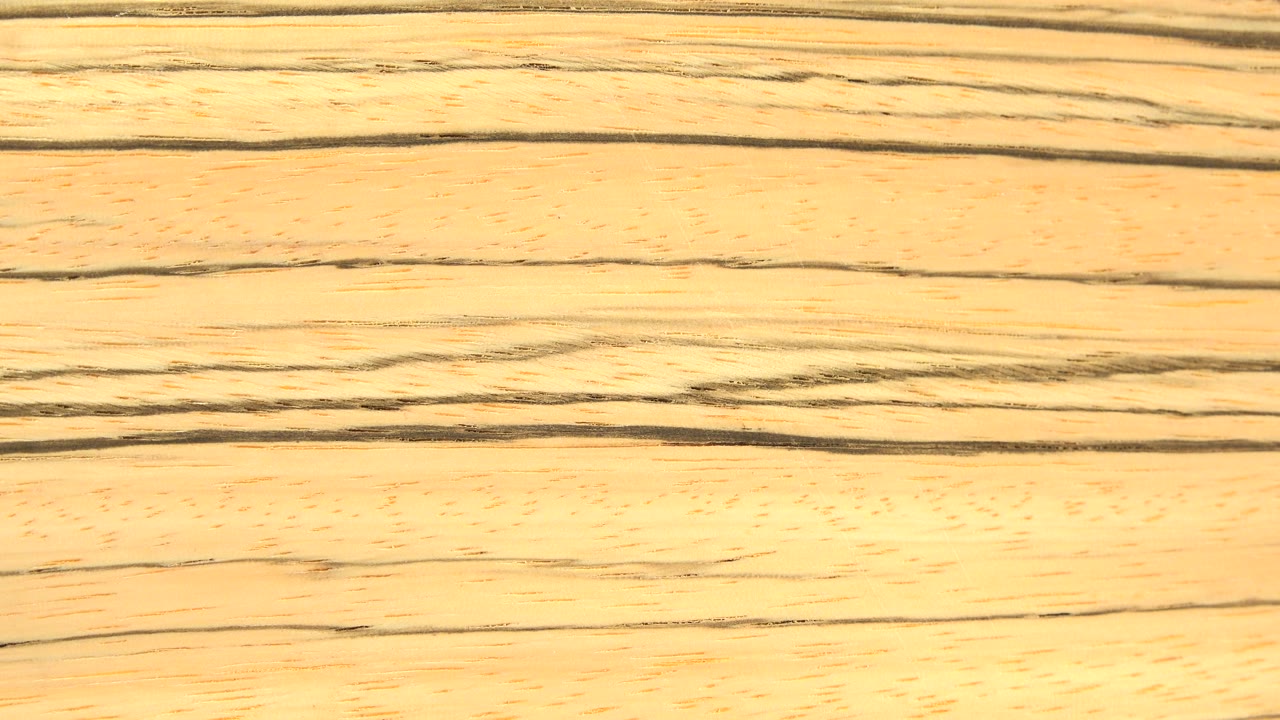 Close view of a golden wood board surface with dark horizontal grain lines and no visible people.