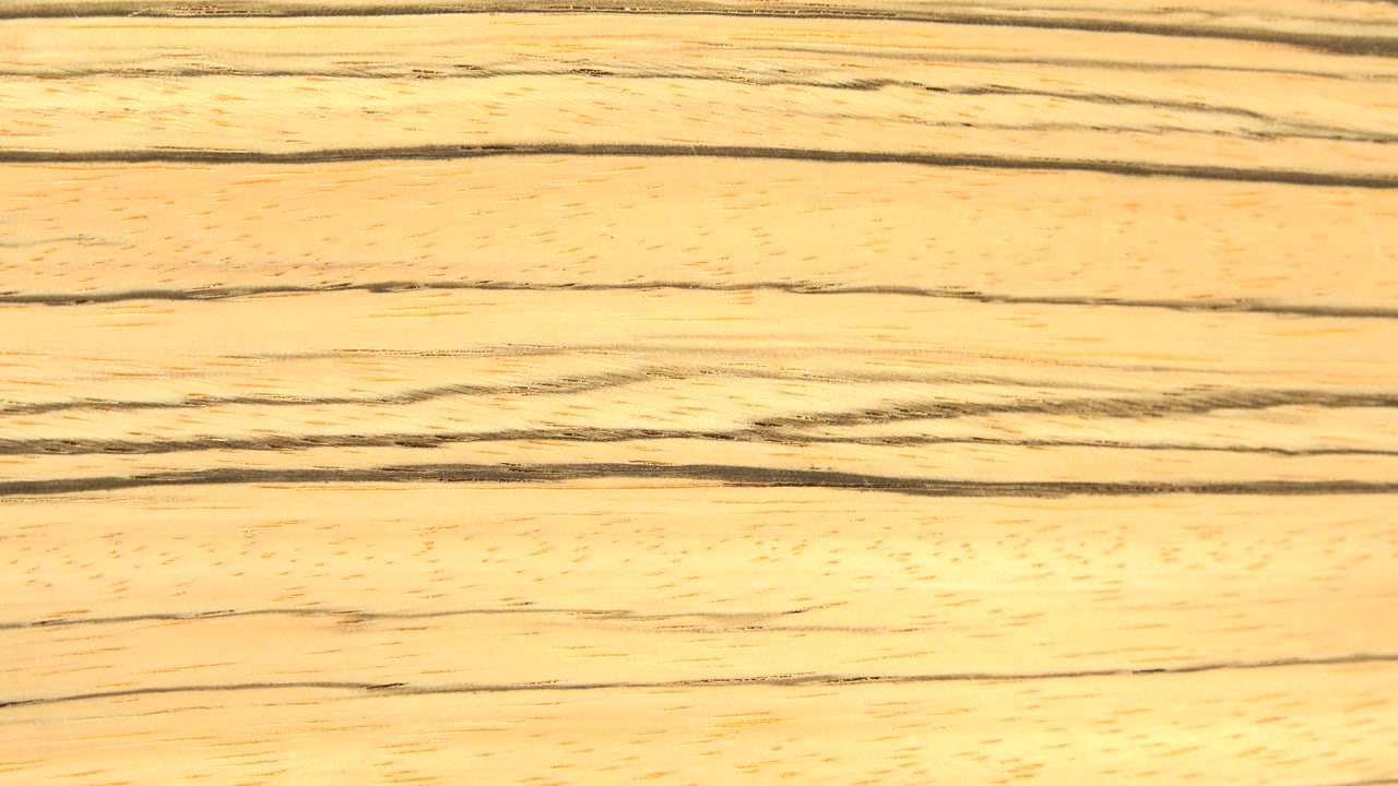 The board remains close to camera, with broad golden wood grain bands running across the frame and no visible people.