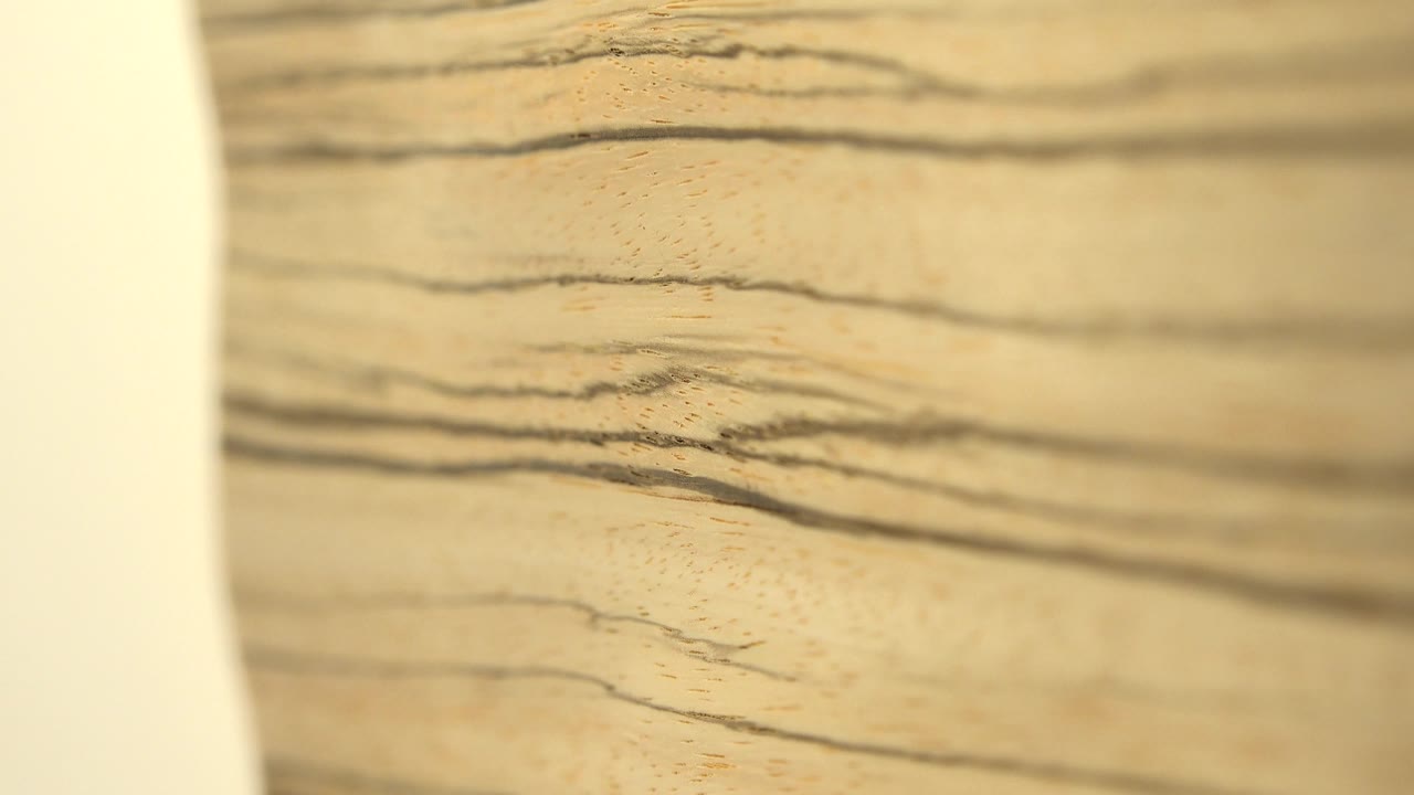 Wood grain fills the frame with a curved white gap at left.