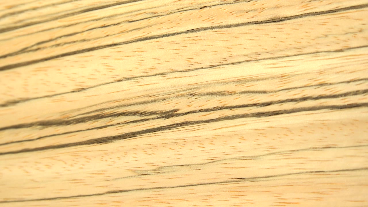 Long dark grain lines run across a pale wooden surface, filling the frame with a slightly shifted close-up pattern and no visible people.