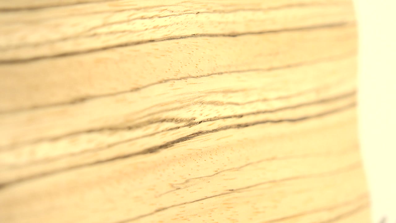 A soft-focus wood surface appears beside a vertical pale strip near the center of the frame, with blurred background texture and no visible people.