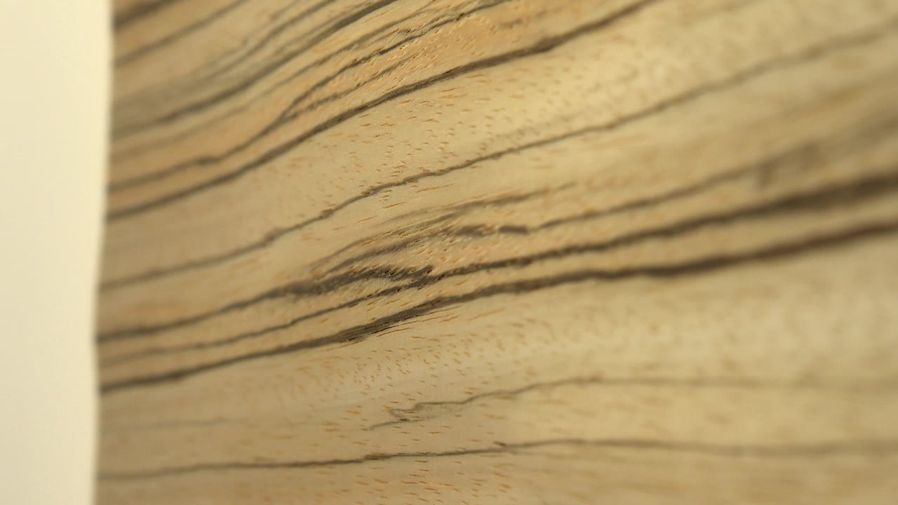 Close view of pale wood with darker tiger-like grain streaks running across the frame, shallow focus, warm yellow cast, and no visible people.