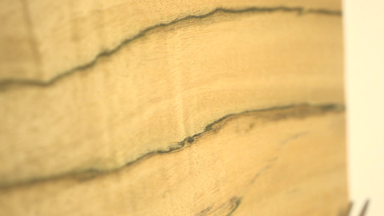 The rotating wood appears softer and slightly blurred, with a dark wavy grain line near the top edge and no visible people.