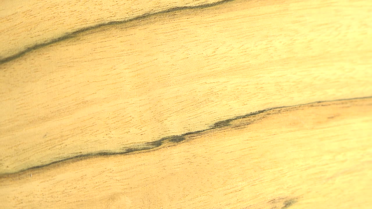 The wood face remains nearly frontal, with a darker horizontal grain line running across the lower portion and no visible people.