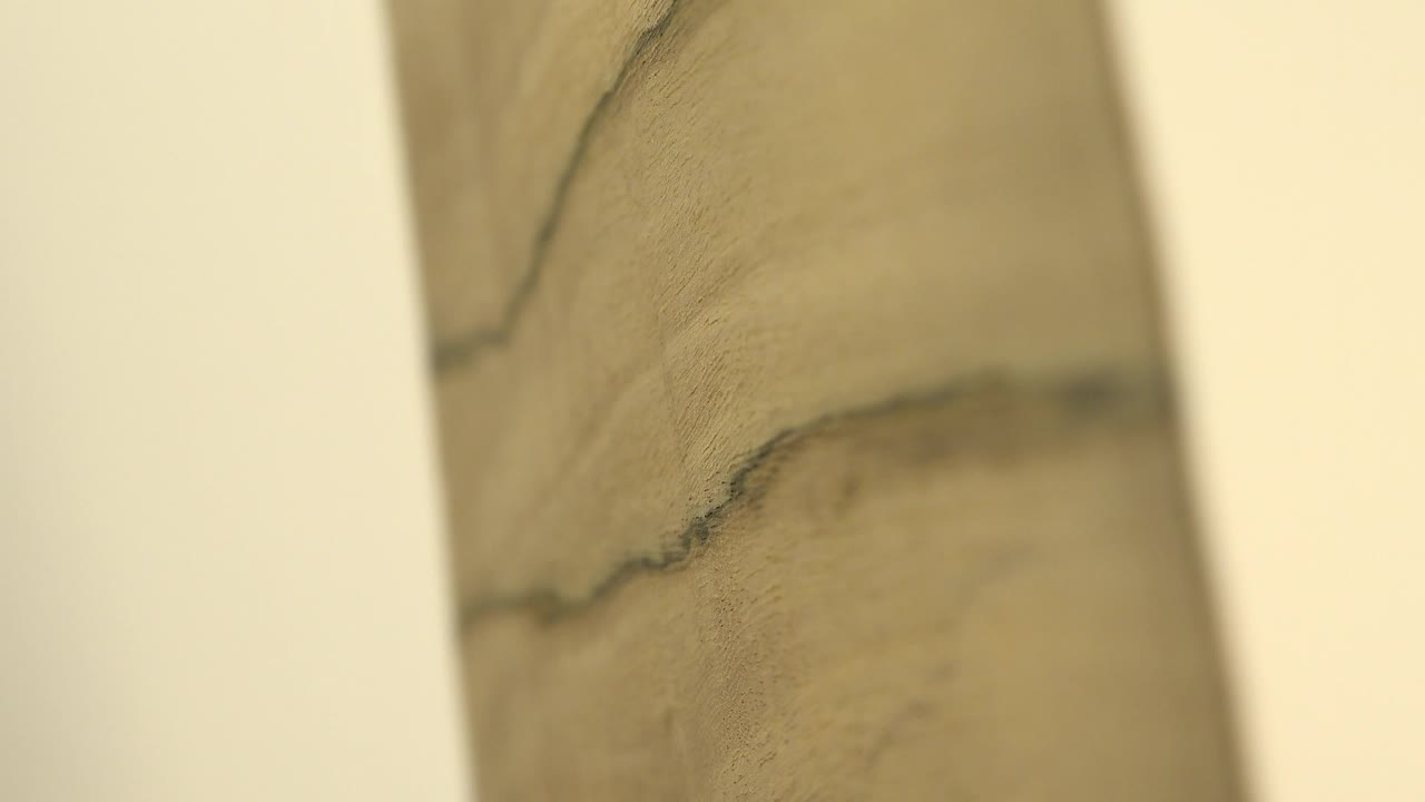 Soft-focused close-up of pale yellow wood grain with dark lines and cream vertical bands, with no visible people.