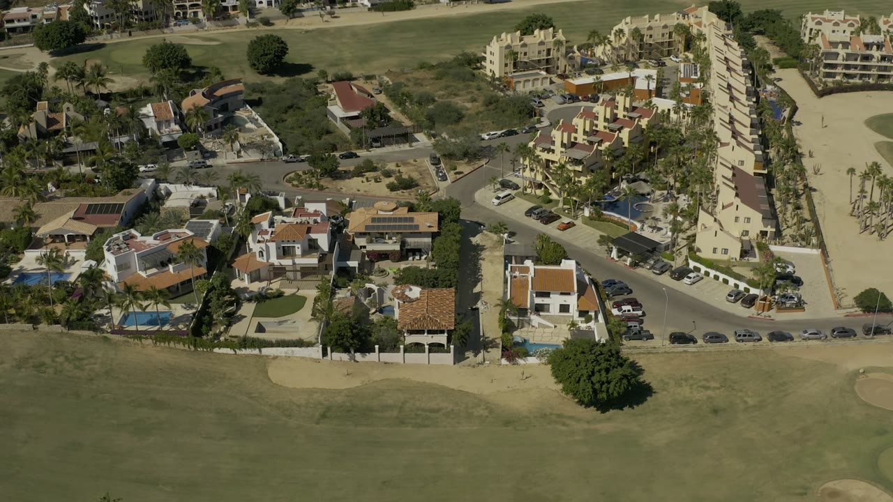 Aerial view of villas, roads, pools, and green fairway.