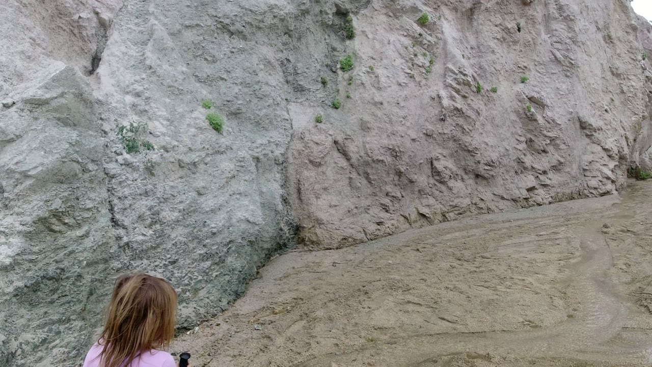 A child appears at the lower left edge as the sandy path runs beside steep eroded rock walls in San Jose Del Cabo, Mexico.