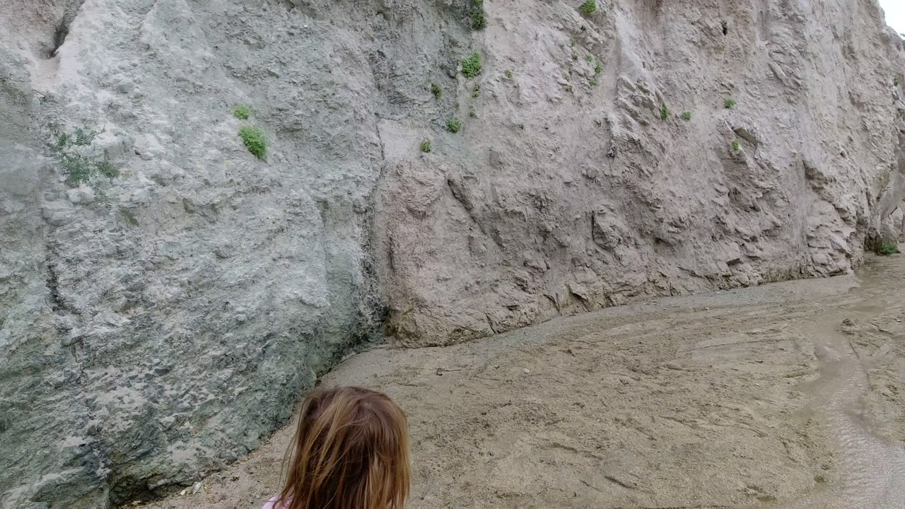 The child is partly visible near the lower center while pale eroded rock walls and sandy ground dominate the San Jose Del Cabo beach frame.